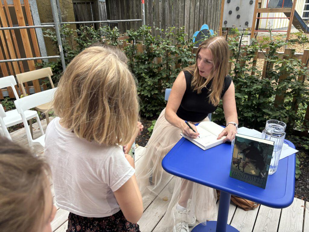 Kinderbuchautorin signiert auf einer Lesung ihr fantastisches Kinderbuch Finsterwelt